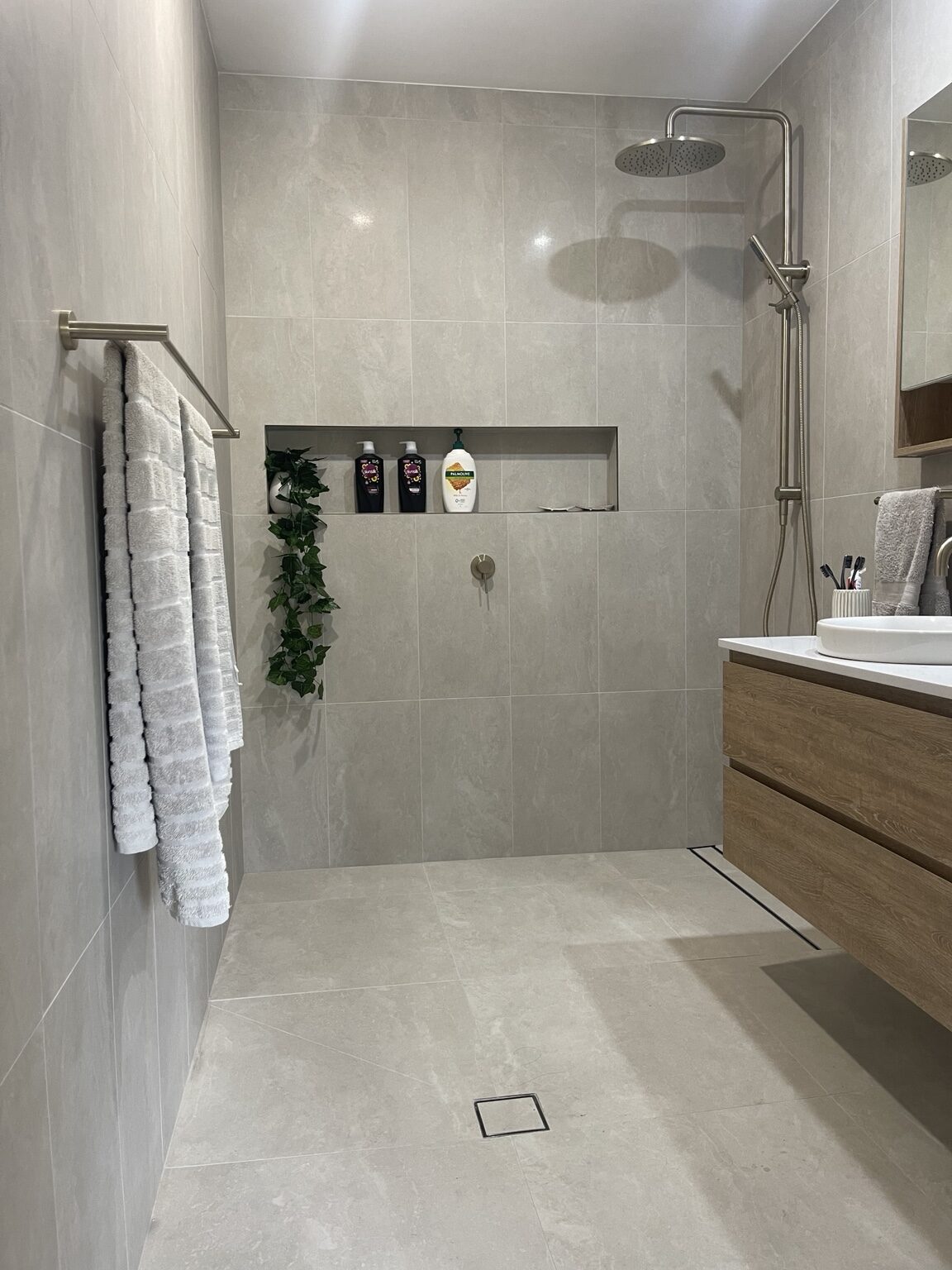 Completed grey tiled bathroom with walk-in shower and floating timber vanity