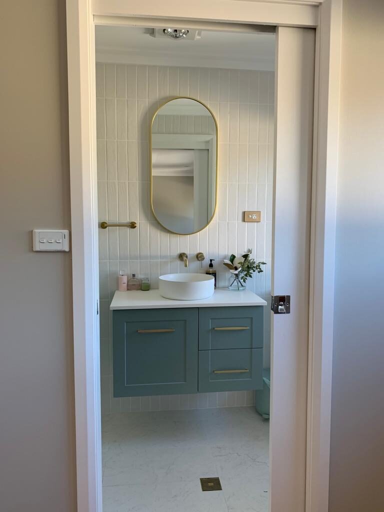 Completed powder room with sage floating vanity and brass mirror